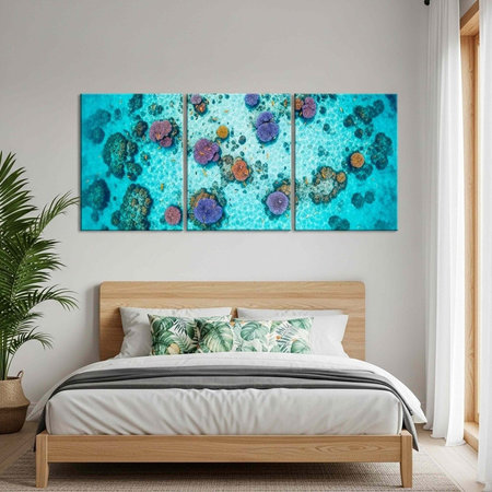 A serene bedroom featuring a wooden bed with white linens, tropical pillows, and a large coral reef painting aboveの写真素材