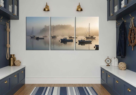 Modern entryway with blue cabinets, nautical decor, and triptych boats artwork on white wall with wooden floorの写真素材