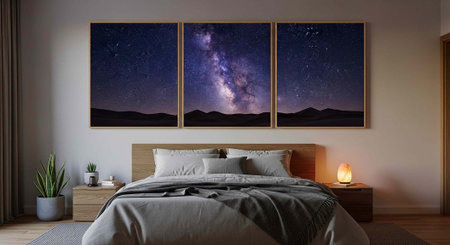 A serene bedroom with a large bed, wooden furniture, and a triptych of starry night sky artwork above the headboard.の写真素材
