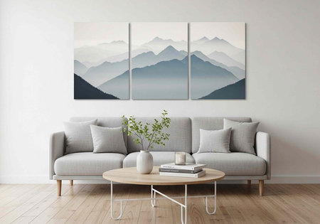 A minimalist living room with a gray couch, round wooden coffee table, and a triptych mountain landscape painting on a white wallの写真素材