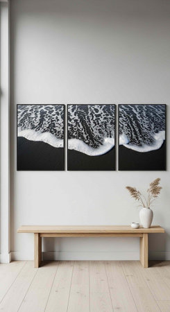 A serene room with a light wood bench, white vase with dried flowers, and three ocean wave paintings on the wallの写真素材