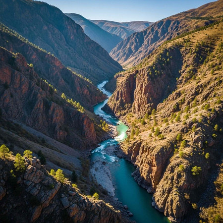 A serene river flows through a rugged mountain landscape with steep cliffs and rocky terrain.の写真素材