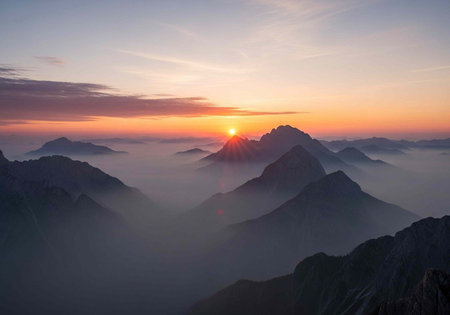 A serene mountain landscape at sunrise with misty valleys and rugged peaksの写真素材