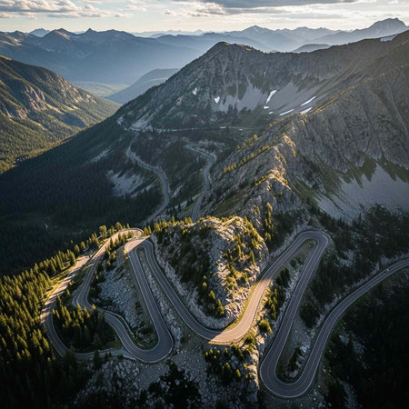 Aerial view of a winding mountain road through a scenic landscape with trees and hillsの写真素材