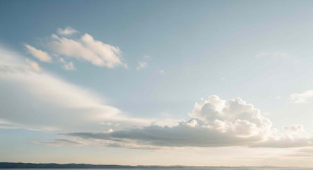A picturesque view of a blue sky with scattered white clouds and a distant horizon lineの写真素材