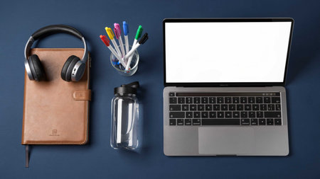 Laptop, headphones, water bottle, notebook and pen on blue background
