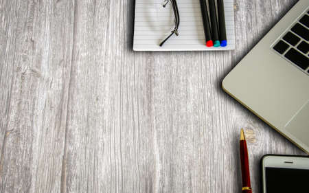 Laptop, smartphone, notepad and pens on a wooden surface, top viewの写真素材