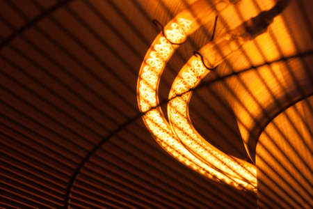 A bright hot filament spiral for a lamp or thermal heater glows orange and gives warmth