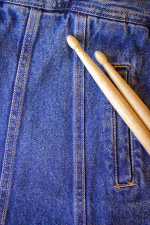 Two drum sticks of oak for rock and roll lie on a denim jeans textile cloth の写真素材