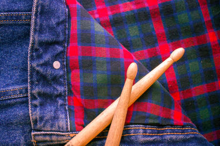 Two drum sticks of oak lie on the fabric of a Scottish cage and jeansの写真素材