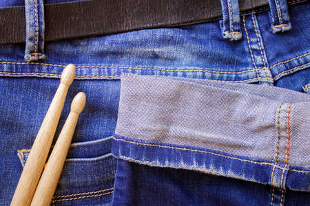 Two drum sticks of oak for rock and roll lie on a denim jeans textile cloth の写真素材