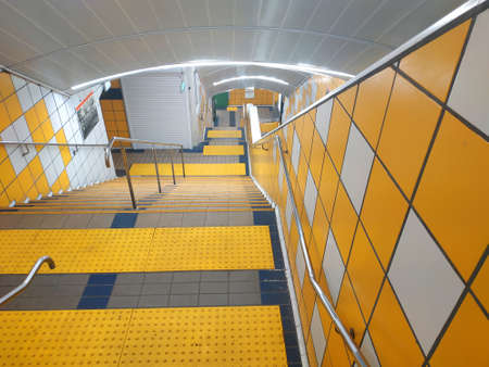 Street urban staircase with yellow illumination leading undergroundの写真素材