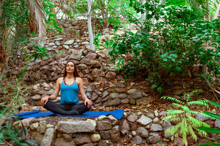 Young woman practicing and training yoga in the parck. Outdoor lady's sportの写真素材