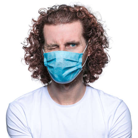 Man in medical mask looks in camera. Scared man in fear of coronavirus stands in protective medical mask against viruses and infections isolated studio. Coronavirus 2019-ncov covid-19 concept.の写真素材