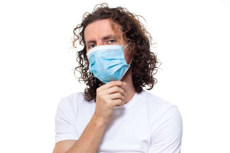 Man in medical mask looks in camera. Man stands in protective medical mask against viruses and infections isolated studio. Pandemic coronavirus epidemic covid-19の写真素材