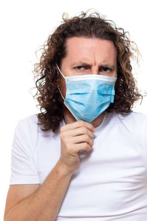 Man in medical mask looks in camera. Man stands in protective medical mask against viruses and infections isolated studio. Pandemic coronavirus epidemic covid-19の写真素材