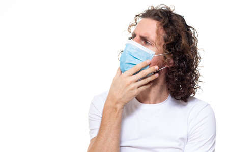 Man in medical mask looks in camera. Man stands in protective medical mask against viruses and infections isolated studio. Pandemic coronavirus epidemic covid-19の写真素材