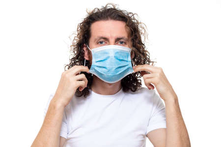 Man in medical mask looks in camera. Man stands in protective medical mask against viruses and infections isolated studio. Pandemic coronavirus epidemic covid-19の写真素材
