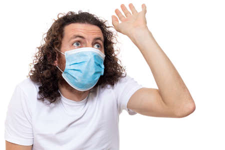 Man in medical mask looks in camera. Man stands in protective medical mask against viruses and infections isolated studio. Pandemic coronavirus epidemic covid-19の写真素材