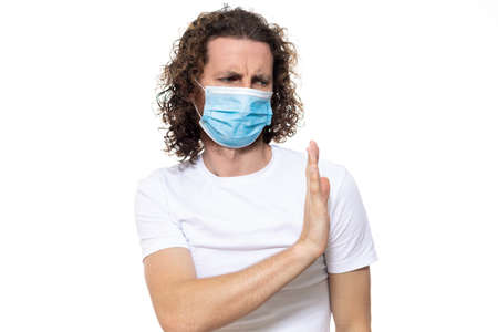 Man in medical mask looks in camera. Man stands in protective medical mask against viruses and infections isolated studio. Pandemic coronavirus epidemic covid-19の写真素材