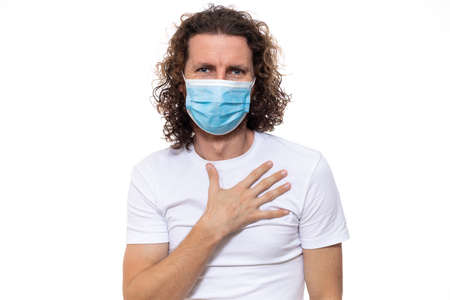 Man in medical mask looks in camera. Man stands in protective medical mask against viruses and infections isolated studio. Pandemic coronavirus epidemic covid-19の写真素材