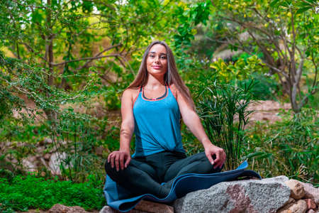 Young woman practicing and training yoga in the parck. Outdoor lady's sportの写真素材