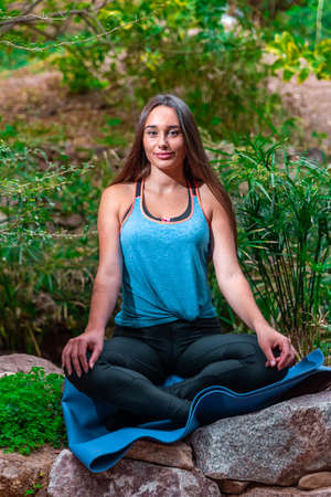 Young woman practicing and training yoga in the parck. Outdoor lady's sportの写真素材