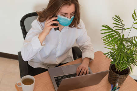 Woman in quarantine for Coronavirus wearing protective mask and smart workingの写真素材