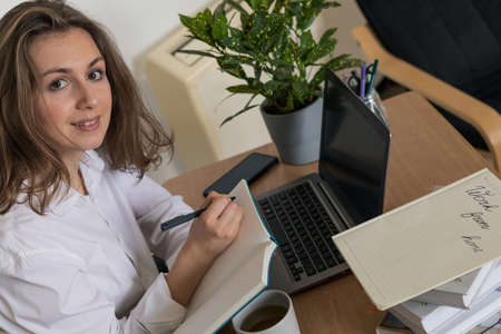 Woman working on laptop at home office while drinling coffee. Web conectionの写真素材