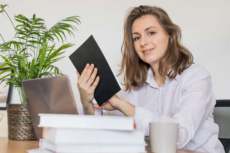 Work from home. Woman drinking coffee and using digital tablet in the morning. Hands on laptopの写真素材