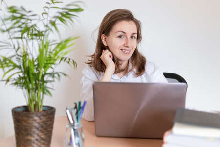 Woman working on laptop at home office while drinling coffee. Web conectionの写真素材