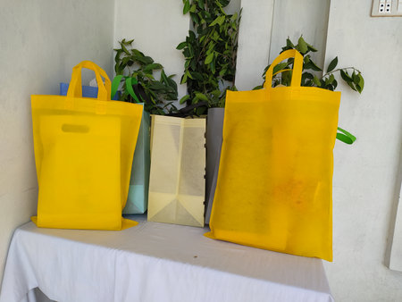 Colorful non woven fabric bags with green leaves isolated on white table. ECO Shopping bags for mock-up. Copy space  Concept for text. New Year and Christmas Gift Bags.の写真素材