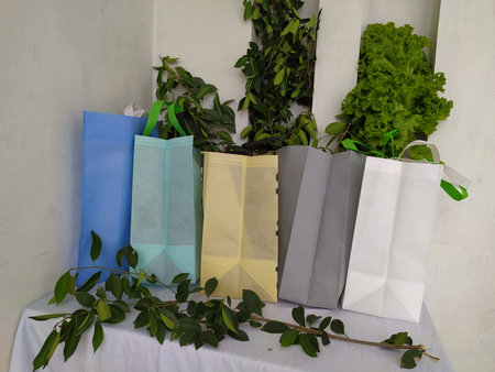 Colorful non woven fabric bags with green leaves isolated on white table. ECO Shopping bags for mock-up. Copy space  Concept for text. New Year and Christmas Gift Bags.の写真素材