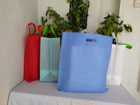 Colorful non woven fabric bags with green leaves isolated on white table. ECO Shopping bags for mock-up. Copy space  Concept for text. New Year and Christmas Gift Bags.の写真素材