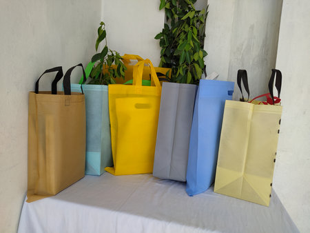 Colorful non woven fabric bags with green leaves isolated on white table. ECO Shopping bags for mock-up. Copy space  Concept for text. New Year and Christmas Gift Bags.の写真素材