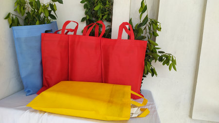 Colorful non woven fabric bags with green leaves isolated on white table. ECO Shopping bags for mock-up. Copy space  Concept for text. New Year and Christmas Gift Bags.の写真素材