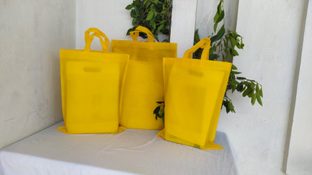 Colorful non woven fabric bags with green leaves isolated on white table. ECO Shopping bags for mock-up. Copy space  Concept for text. New Year and Christmas Gift Bags.の写真素材