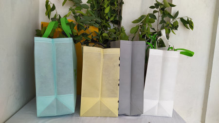 Colorful non woven fabric bags with green leaves isolated on white table. ECO Shopping bags for mock-up. Copy space  Concept for text. New Year and Christmas Gift Bags.の写真素材