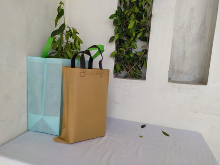 Colorful non woven fabric bags with green leaves isolated on white table. ECO Shopping bags for mock-up. Copy space  Concept for text. New Year and Christmas Gift Bags.の写真素材