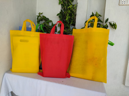 Colorful non woven fabric bags with green leaves isolated on white table. ECO Shopping bags for mock-up. Copy space  Concept for text. New Year and Christmas Gift Bags.の写真素材