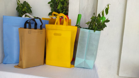 Colorful non woven fabric bags with green leaves isolated on white table. ECO Shopping bags for mock-up. Copy space  Concept for text. New Year and Christmas Gift Bags.の写真素材