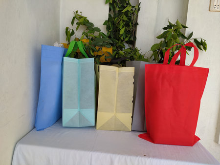 Colorful non woven fabric bags with green leaves isolated on white table. ECO Shopping bags for mock-up. Copy space  Concept for text. New Year and Christmas Gift Bags.の写真素材