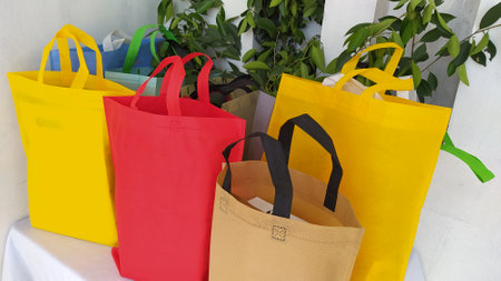 Colorful non woven fabric bags with green leaves isolated on white table. ECO Shopping bags for mock-up. Copy space  Concept for text. New Year and Christmas Gift Bags.の写真素材