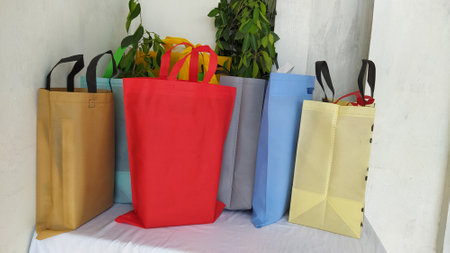 Colorful non woven fabric bags with green leaves isolated on white table. ECO Shopping bags for mock-up. Copy space  Concept for text. New Year and Christmas Gift Bags.の写真素材