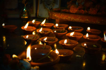 Traditional earthen lamps arranged in a beautiful pattern with colored rangoli (powder) designs on...