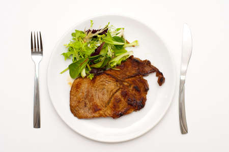 Juisy stake with salad on a plate, isolated white backgroundの写真素材