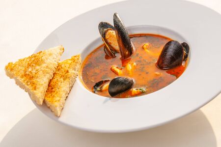 Oyster soup with vegetables and two pieces of toast on white backgroundの写真素材