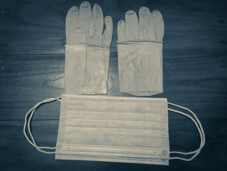 A pair of rubber medical gloves, surgical mask on a wooden table.vの写真素材