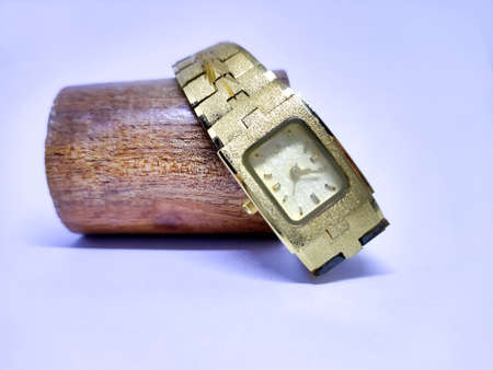 A golden woman watch placed on a wooden structure.の写真素材