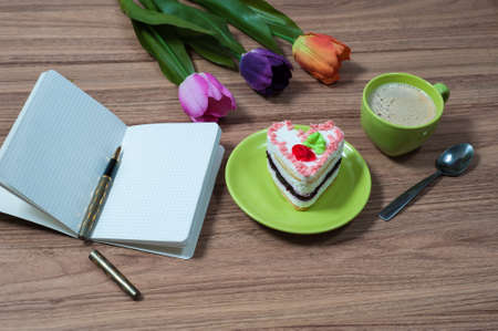 green cup of the coffee and a copybook on a wooden tableの写真素材